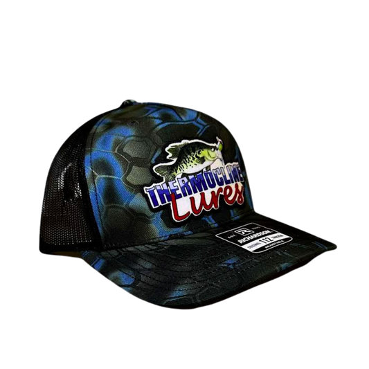 Side profile of the Thermocline Lures blue and black Kryptek camo trucker hat, featuring a breathable black mesh back and an adjustable snap closure.