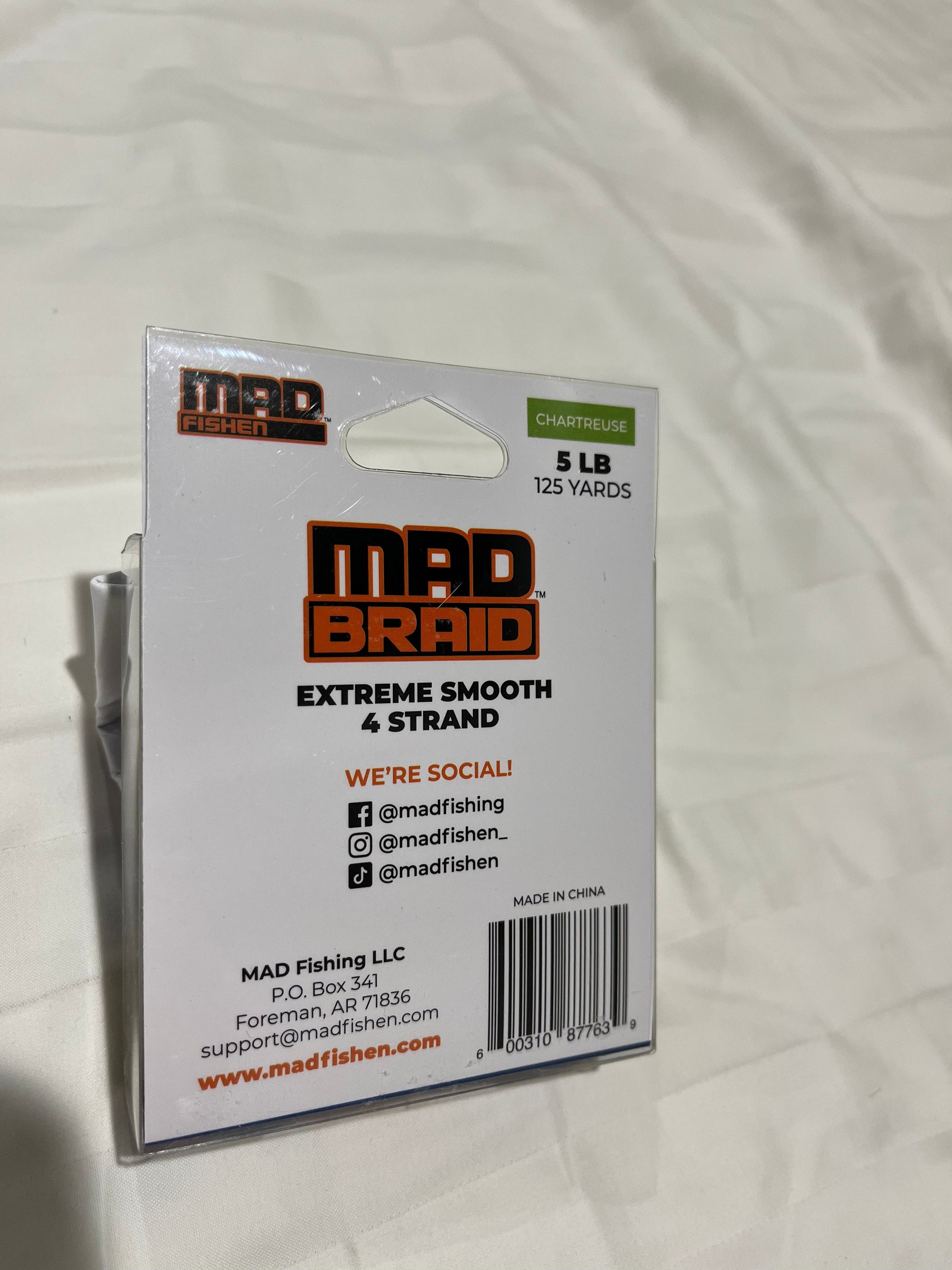 Back view of Mad Braid braided fishing line in chartreuse, displaying product details, social media handles, and company information.