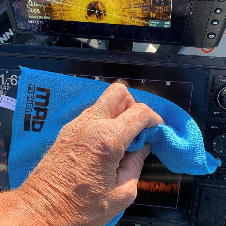 Angler using a MadFishen microfiber cloth to clean a fish finder screen. The perfect duo for maintaining clear, glare-free marine electronics while fishing.