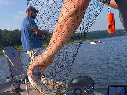 Angler using The Button Digital Fish Counter while netting a fish on a boat. A must-have tool for keeping track of catches effortlessly during fishing trips.